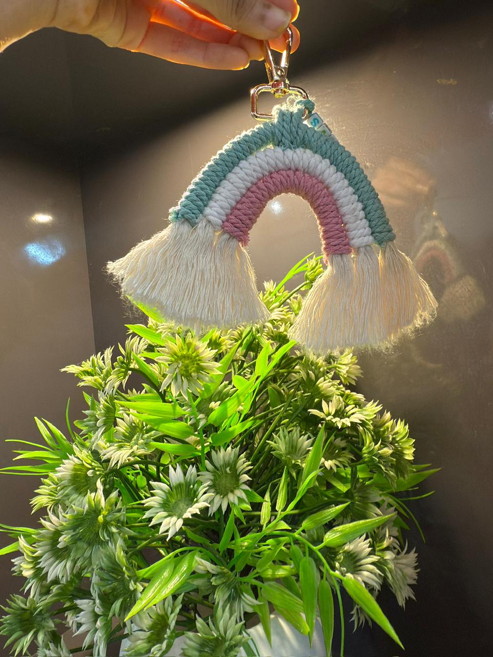Rainbow macramé keychain above green foliage